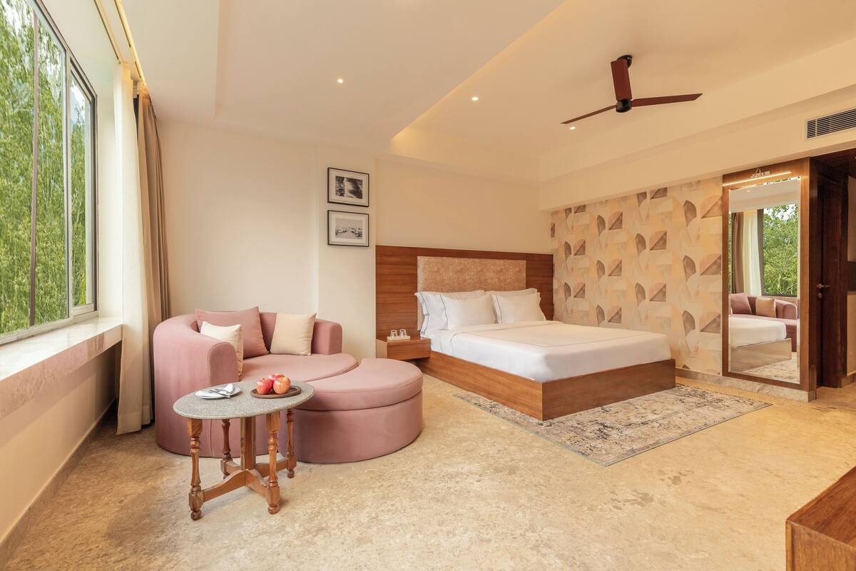 Un dormitorio moderno con una cama, un sofá, una mesita y una ventana con cortinas.