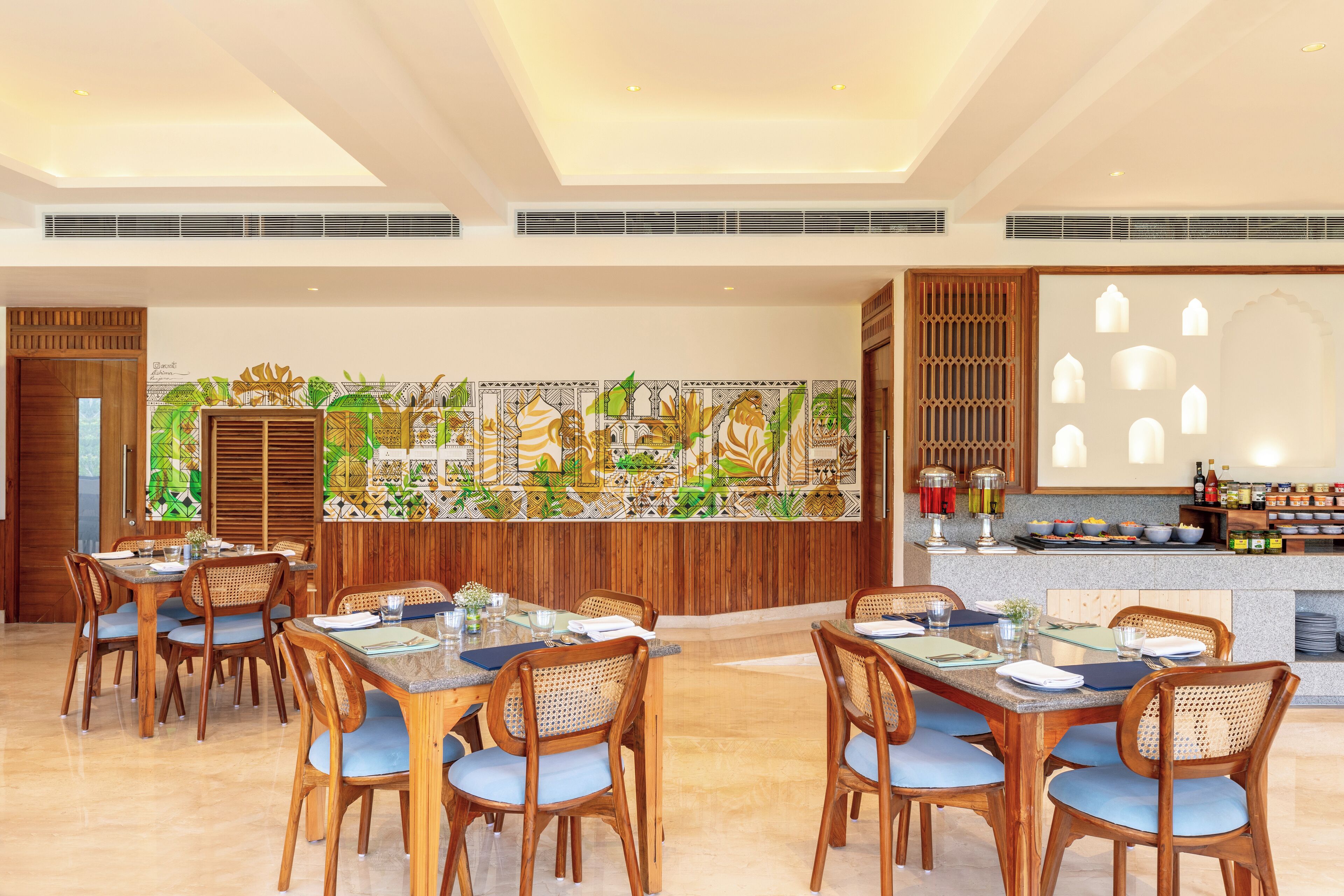 A dining area with wooden tables and chairs, a decorative wall, and a bar area with bottles and glasses.