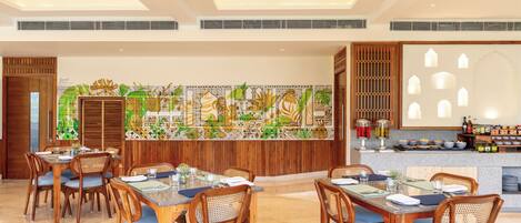 A dining area with wooden tables and chairs, a decorative wall, and a bar area with bottles and glasses.