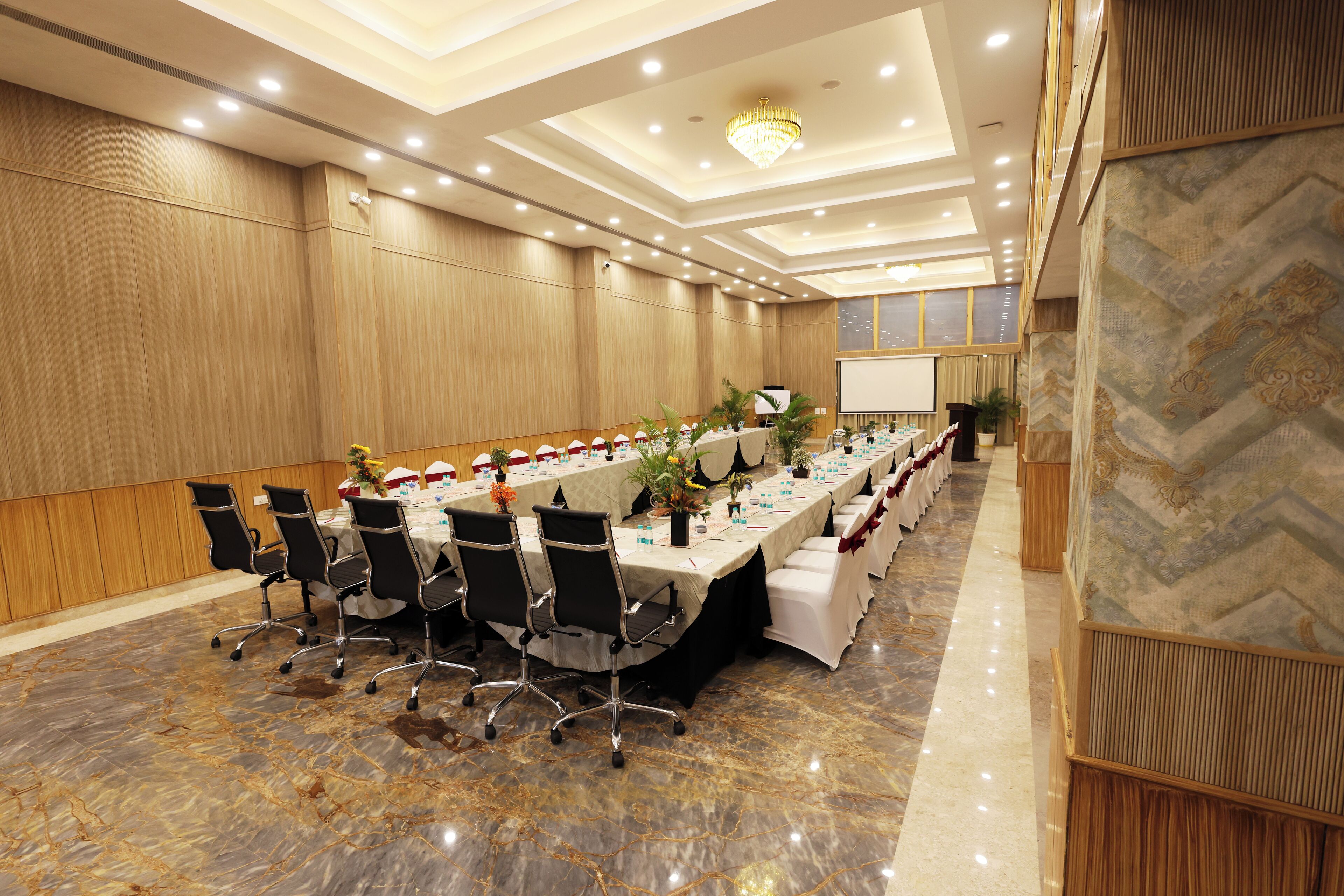 A conference room with a long table, chairs, and a projector screen.