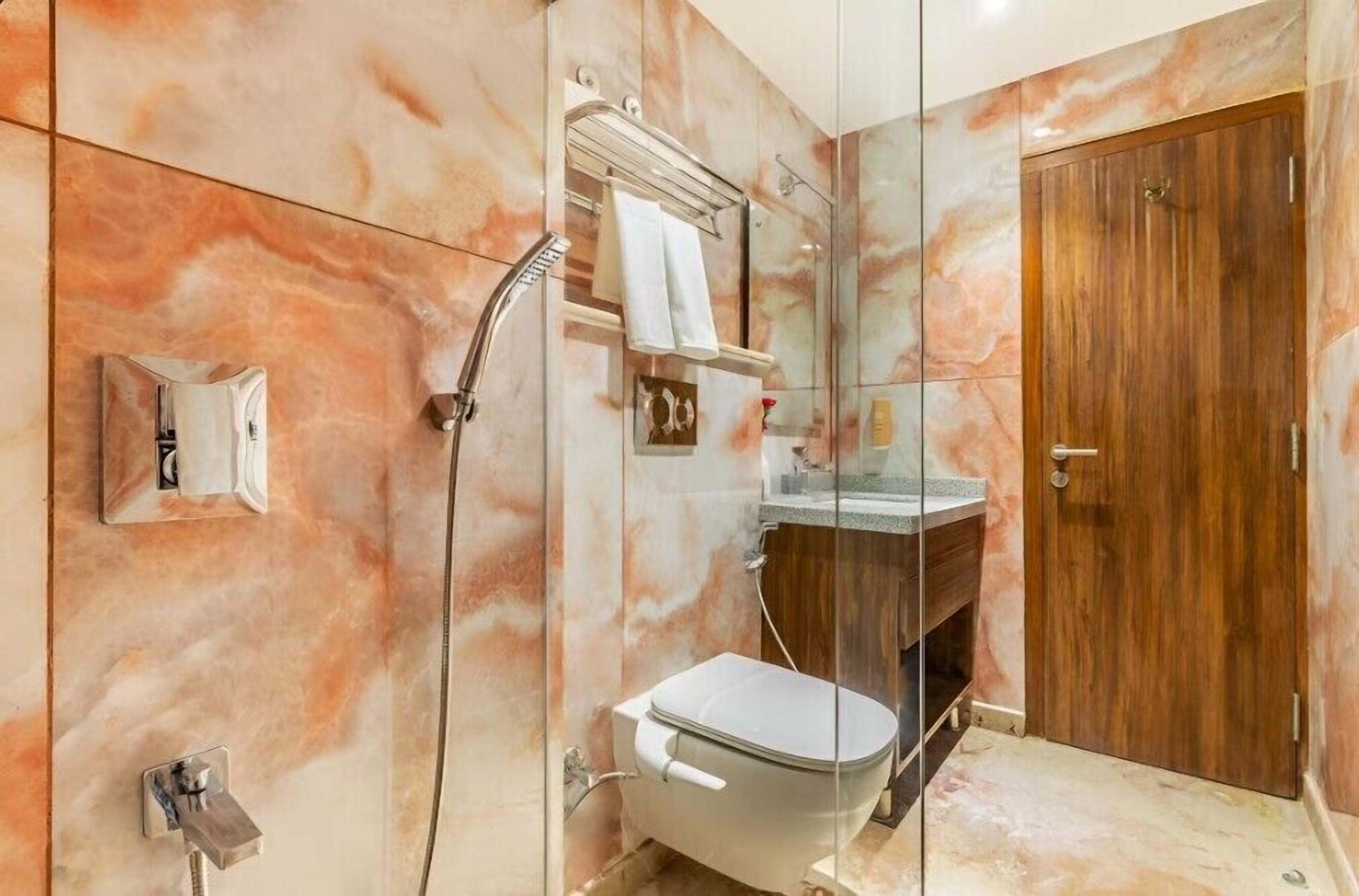 Une salle de bain moderne avec une douche à parois de verre, une porte en bois et un mur en marbre.