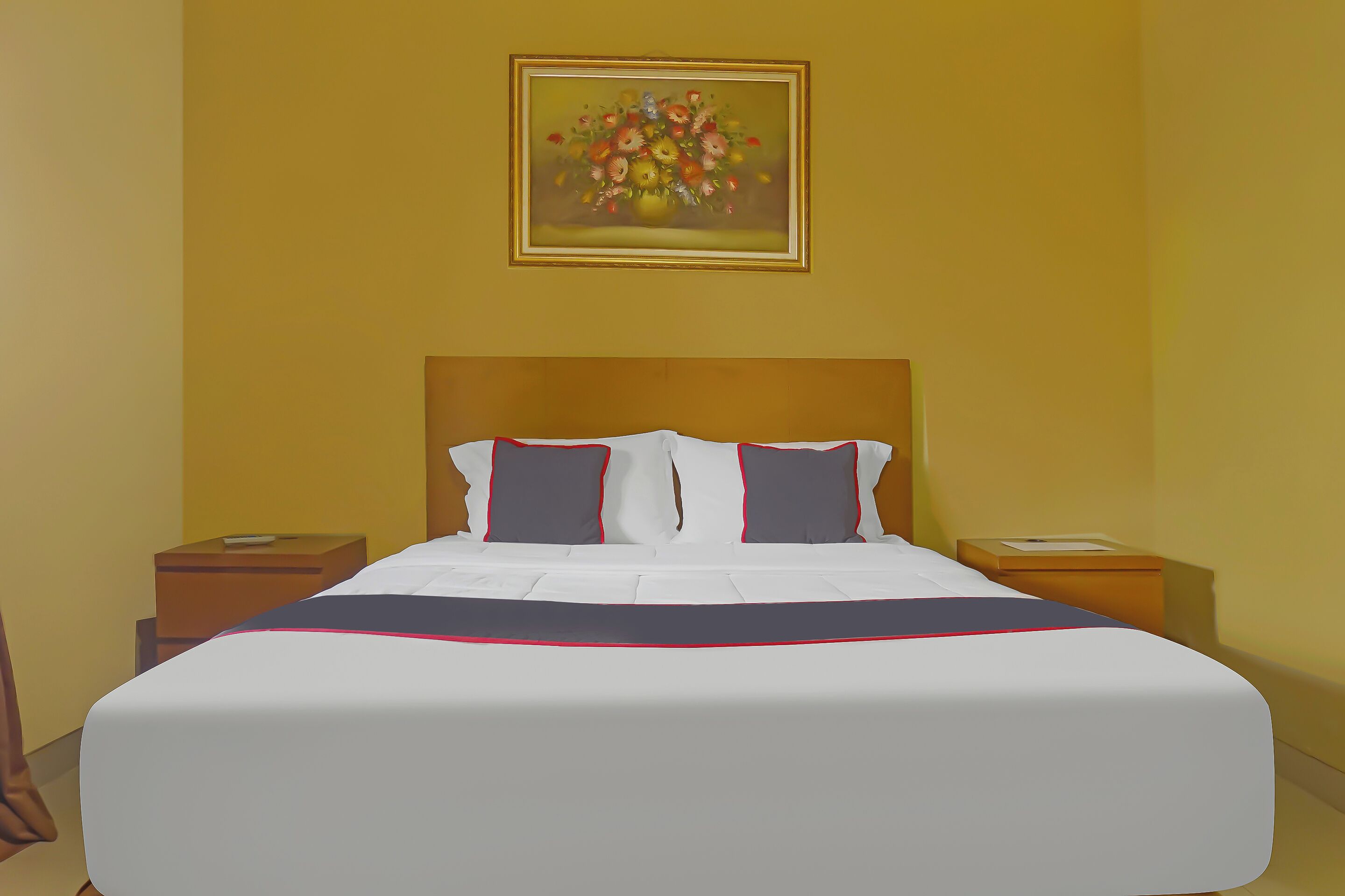 Ein Hotelzimmer mit einem großen Bett, zwei Nachttischen, einem Schrank und einem Bild an der Wand sowie einem Fenster.