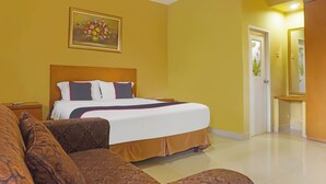 A hotel room with a large bed, a sofa, a painting on the wall, and a door with a mirror. - Capital O 92836 Villa Kampoeng Katineung (Cipanas)