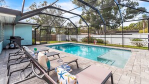 A covered swimming pool with lounge chairs and a barbecue grill. - Close to Beach! Heated Pool! Pets OK! Private/Fenced-in Backyard! Rock to Beach Home ~ Largo, FL (Largo)