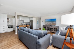 A modern living room with a grey sectional sofa, a wooden coffee table, and a TV on a cabinet.