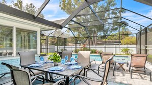 A covered outdoor dining area with a pool, tables, chairs, and a glass enclosure. - Close to Beach! Heated Pool! Pets OK! Private/Fenced-in Backyard! Rock to Beach Home ~ Largo, FL (Largo)