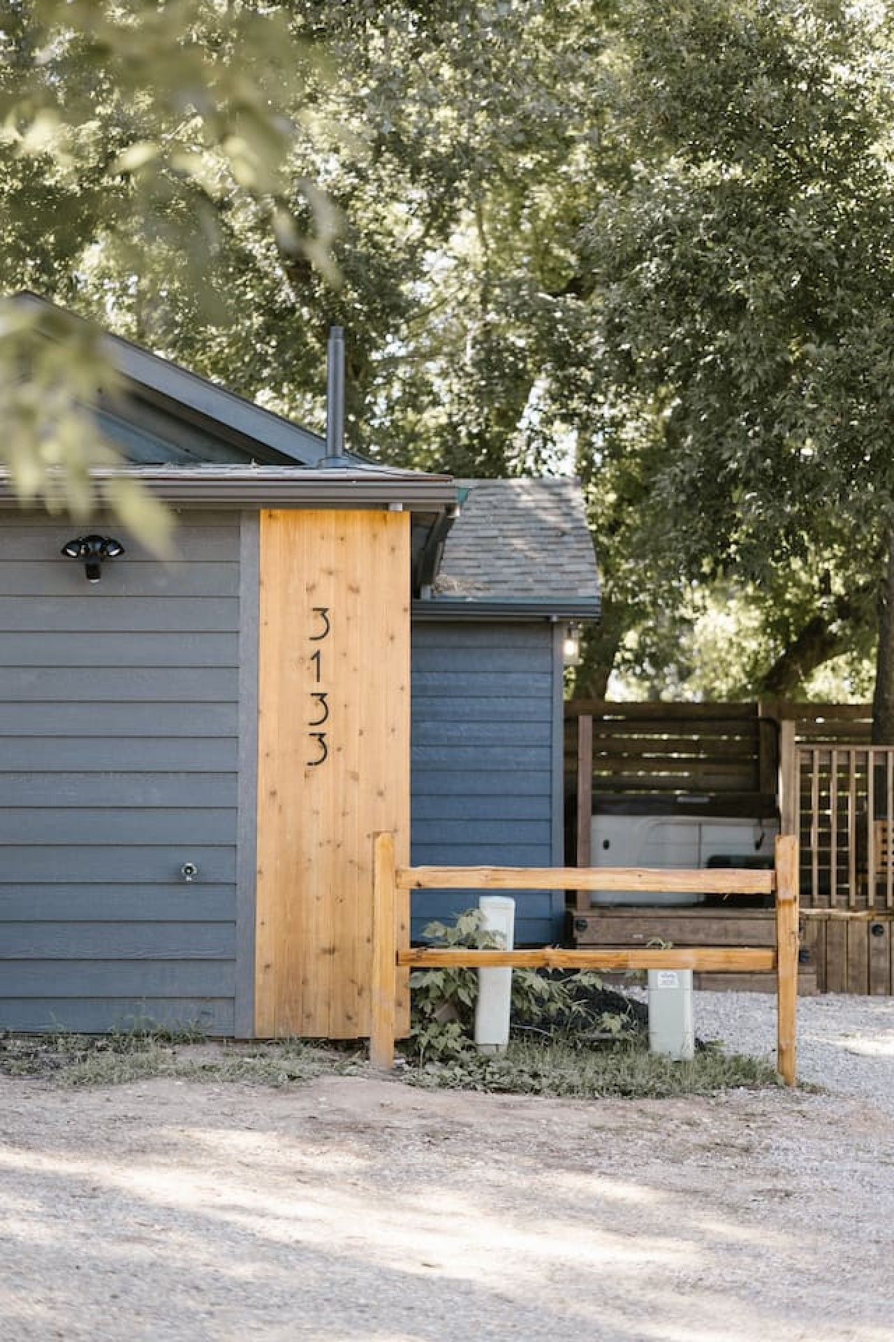 A small, single-story building with a grey exterior and a wooden door marked '313'.