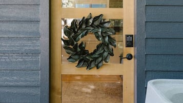 A wooden door with a wreath, a keypad lock, and a doormat.