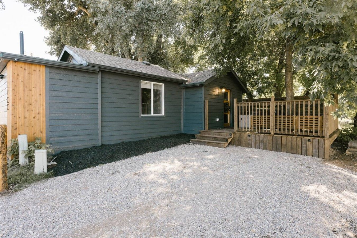 Un petit bâtiment d’un seul étage, avec une allée en gravier et une terrasse en bois.