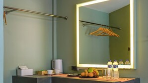 A bathroom with a vanity, a mirror with lights, a towel rack, a stool, and toiletries. - Maiiam Bungalows (Karon)