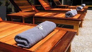 A row of wooden lounge chairs with towels, arranged outdoors. - Maiiam Bungalows (Karon)
