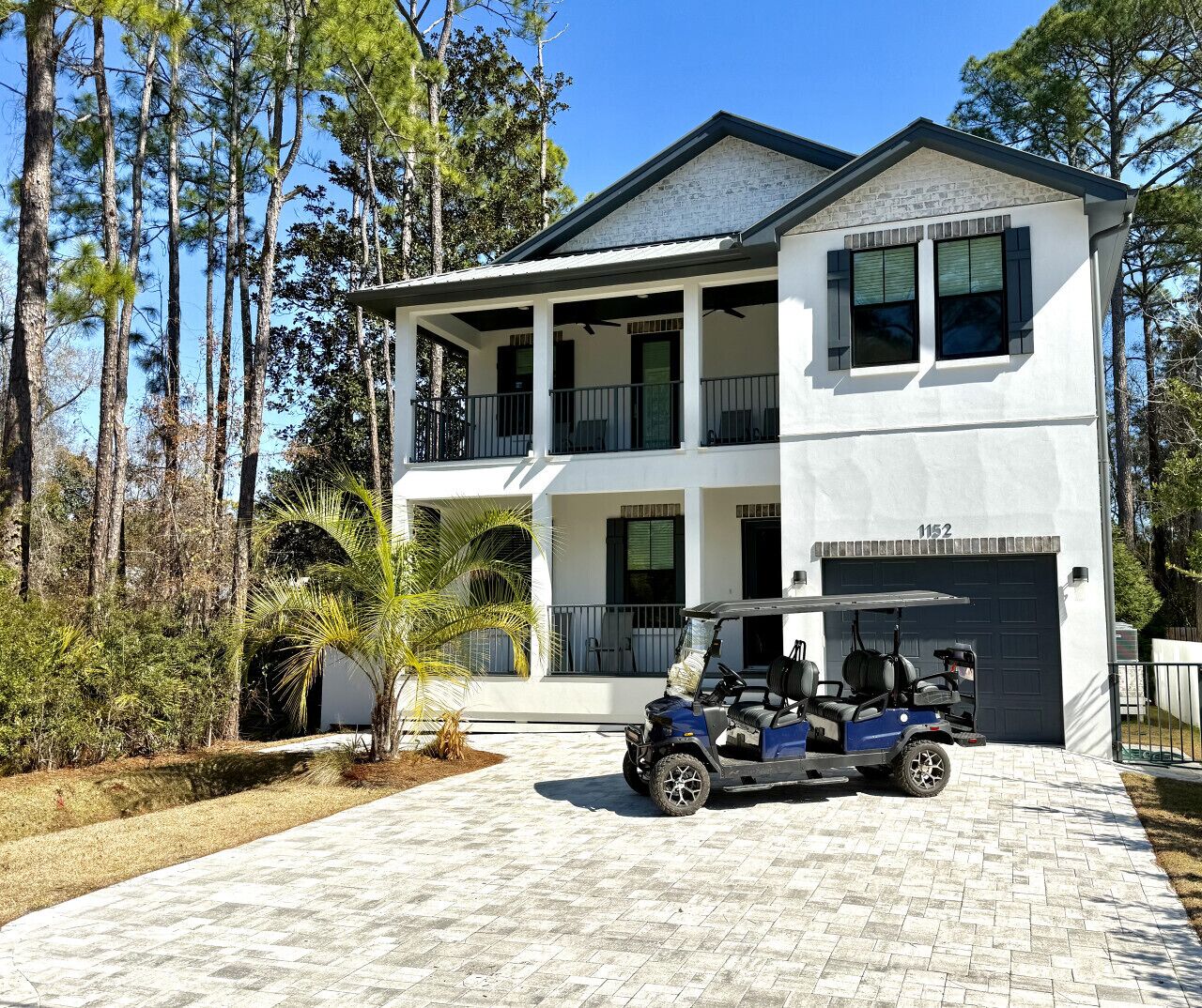 A two-story house with a garage, a covered porch, and a golf cart parked in front.