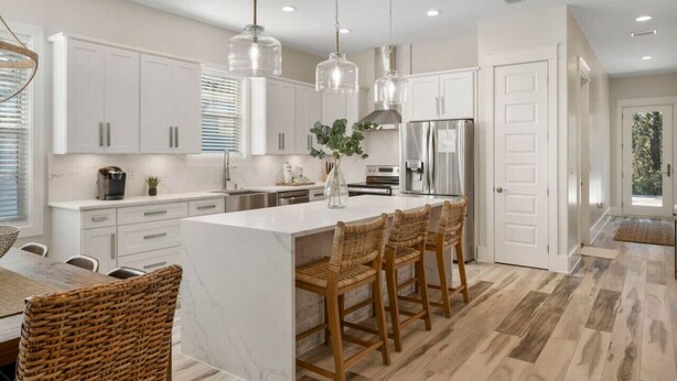 A modern kitchen with white cabinets, a marble island, wicker bar stools, and pendant lighting. - Santa Rosa Beach|Heated Pool|Pet Friendly|Hot Tub|Boat Parking (Santa Rosa Beach)