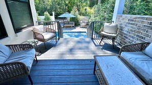 A covered outdoor patio with wicker furniture, a pool, and a view of a wooded area. - Santa Rosa Beach|Heated Pool|Pet Friendly|Hot Tub|Boat Parking (Santa Rosa Beach)