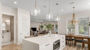A modern kitchen with a large island, pendant lights, and a dining area with wooden chairs. - Santa Rosa Beach|Heated Pool|Pet Friendly|Hot Tub|Boat Parking (Santa Rosa Beach)
