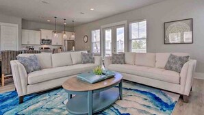 A modern living room with a sectional sofa, a coffee table, and a blue rug. - Blue Mountain Beach Home w/ Golf Cart|Bikes|Community Pool & Hot Tub (Santa Rosa Beach)