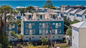 A coastal residential area with multiple two-story buildings, some with balconies, and a view of the ocean.