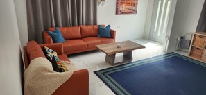 A living room with a sofa, coffee table, and a blue rug.