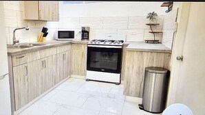 Una cucina compatta con lavello, piano cottura, forno a microonde e cestino.