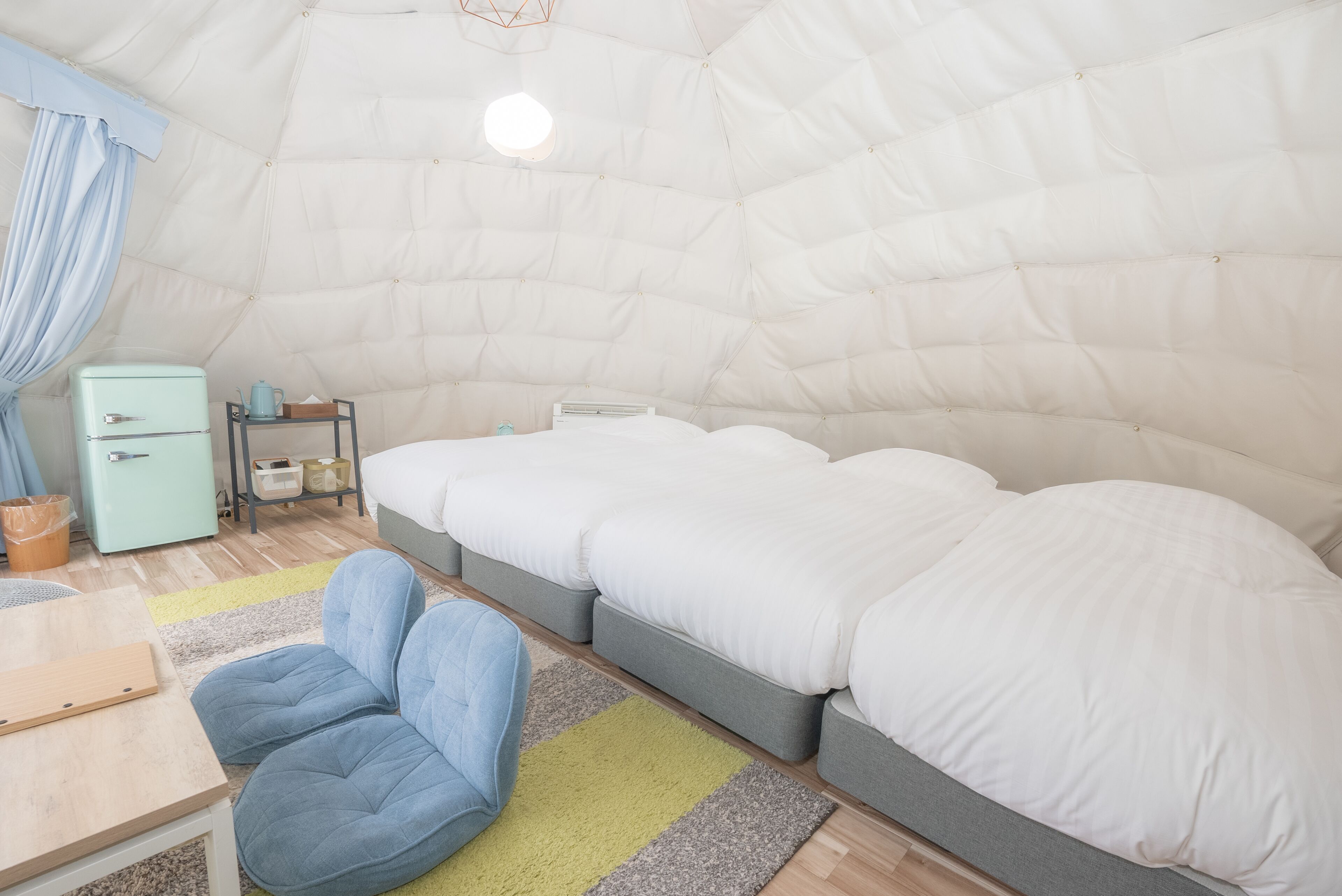 Een knus, compacte kamer met een bed, een klein tafeltje en een stoel.