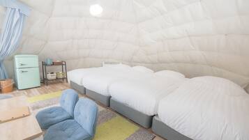 Een knus, compacte kamer met een bed, een klein tafeltje en een stoel.
