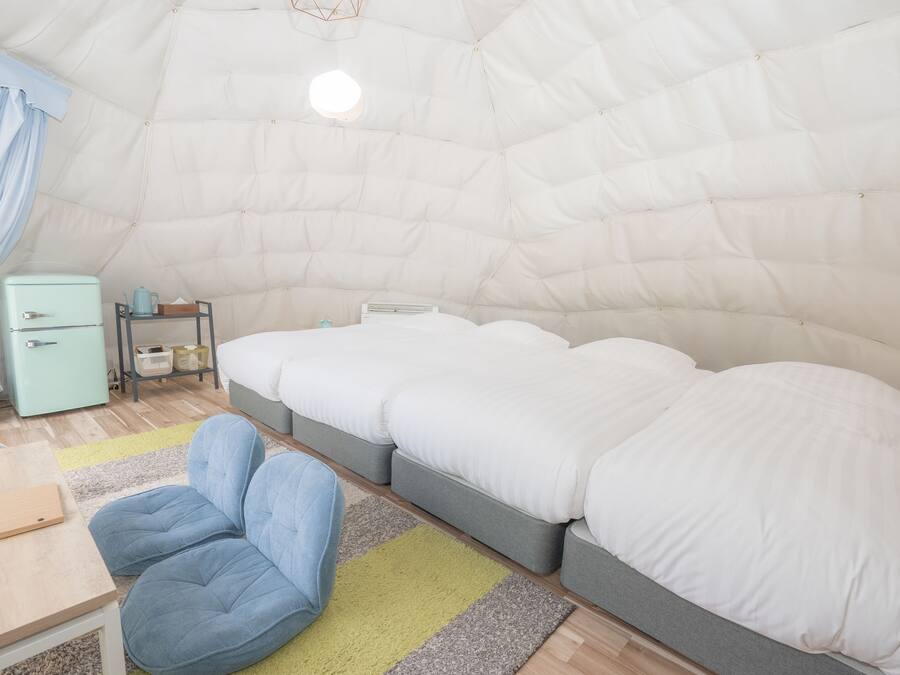 Een knus, compacte kamer met een bed, een klein tafeltje en een stoel.