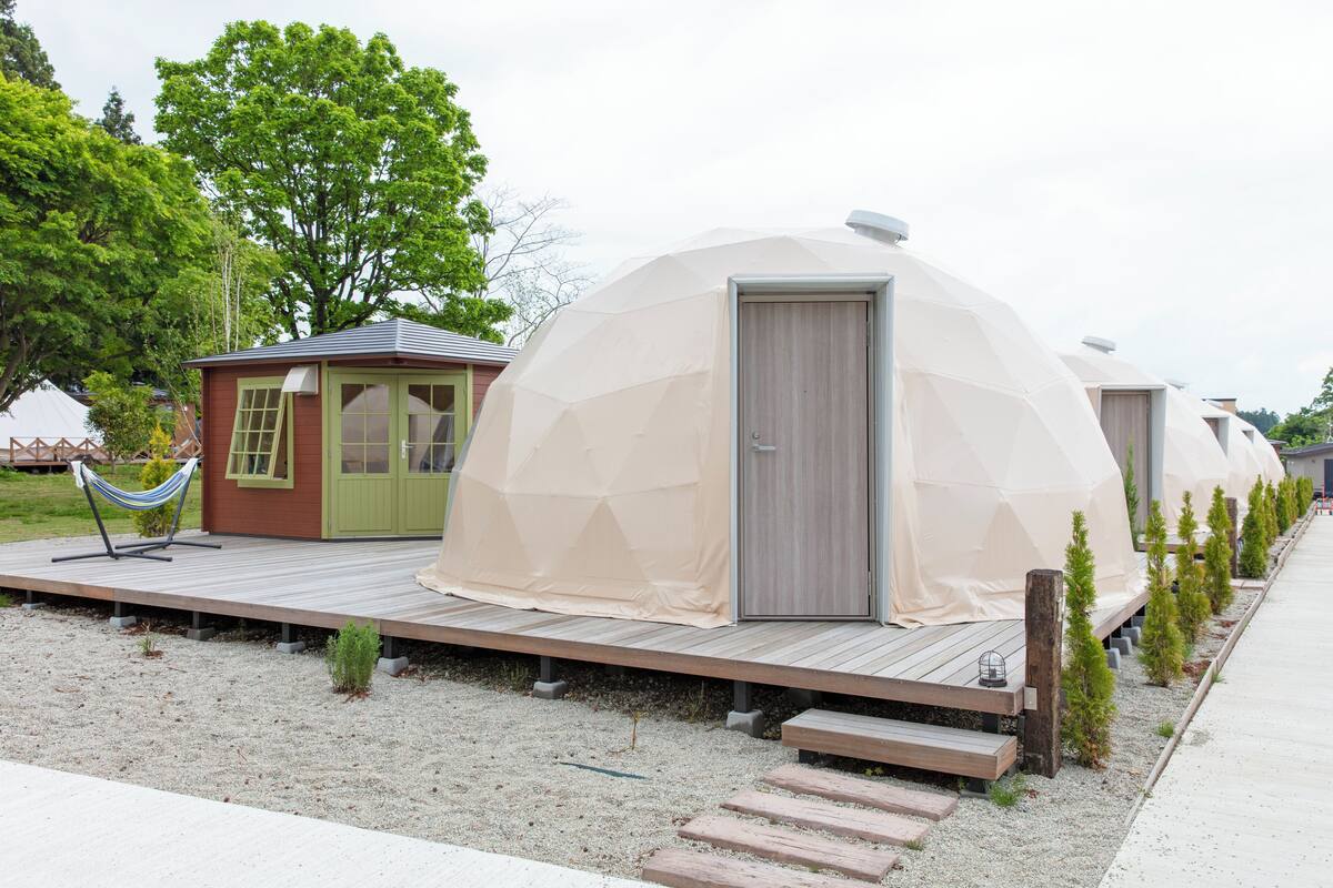 Geodesic dome-style cabins with a wooden deck and a small attached structure with a green door.