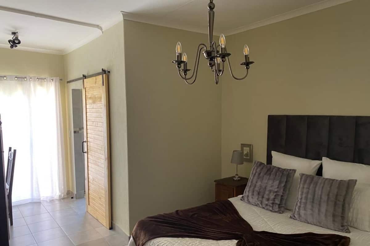Une chambre à coucher comprenant un lit, une table de chevet, une lampe, un lustre et une porte coulissante.