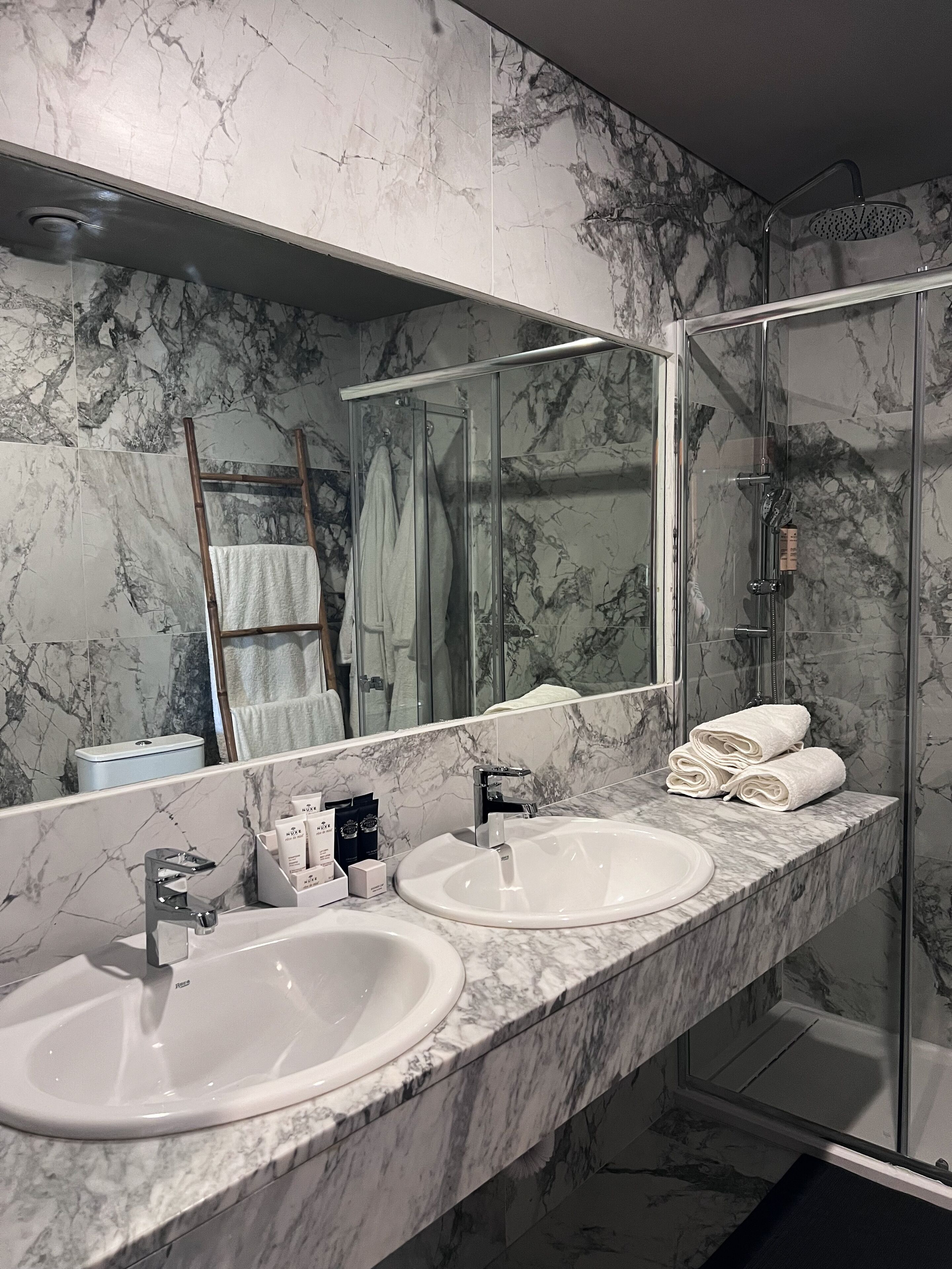 Un baño con dos lavamanos, un espejo grande y una cabina de ducha de vidrio.