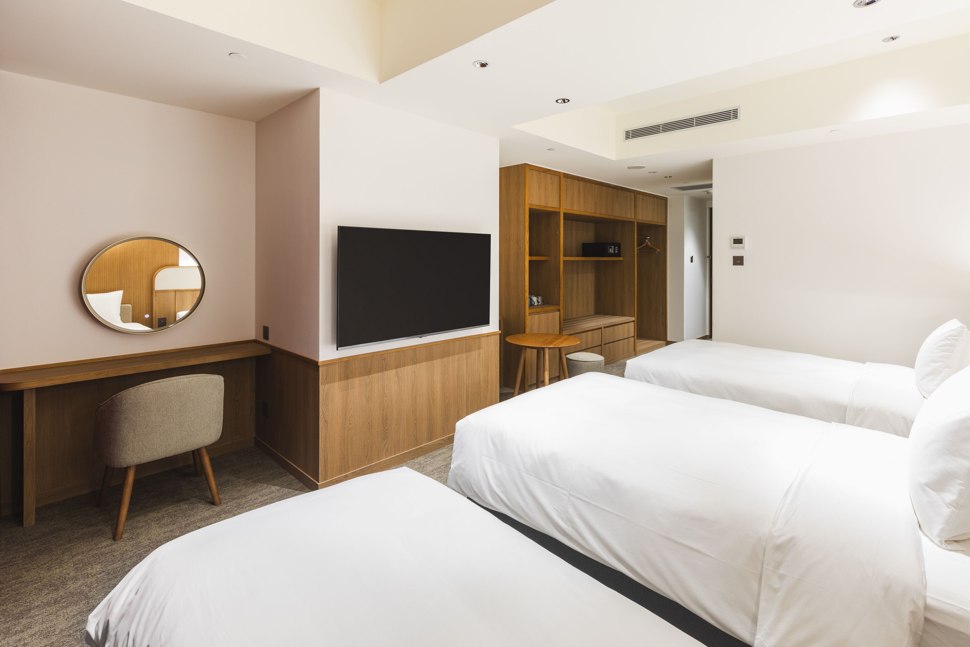 A hotel room with a bed, a desk, a chair, a TV, and a wardrobe.