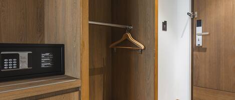A hotel room with a wooden wardrobe, a built-in microwave, and a hanging coat rack.