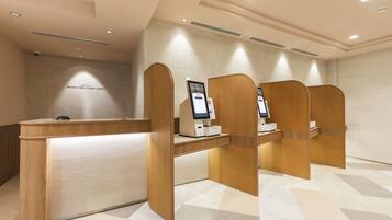 A modern reception area with a wooden reception desk and individual privacy booths, each equipped with a digital kiosk.