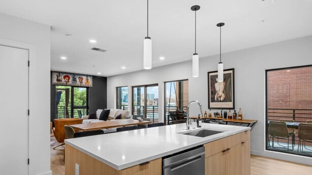 A modern kitchen with a central island, pendant lights, and a view of the city. - Downtown Nashville | Pool, Gym + Skyline Views | Bridgestone (Nashville)