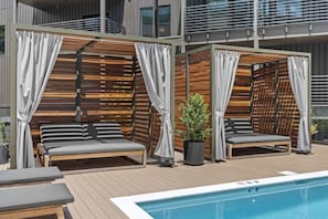 Relax by the pool surrounded by lush greenery and shaded seating areas.