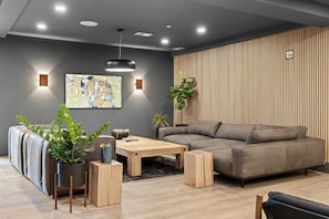 Relax in this stylish living room with a sofa, coffee table, and potted plant, set against a contemporary backdrop.
