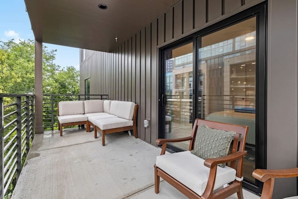 Relax on the balcony with a sofa and two chairs, taking in the view of the surrounding area.