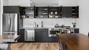 A modern kitchen with a stainless steel refrigerator, dishwasher, and stove. - Riverfront Group Suite: Walk to Broadway & Titans Stadium (Nashville)