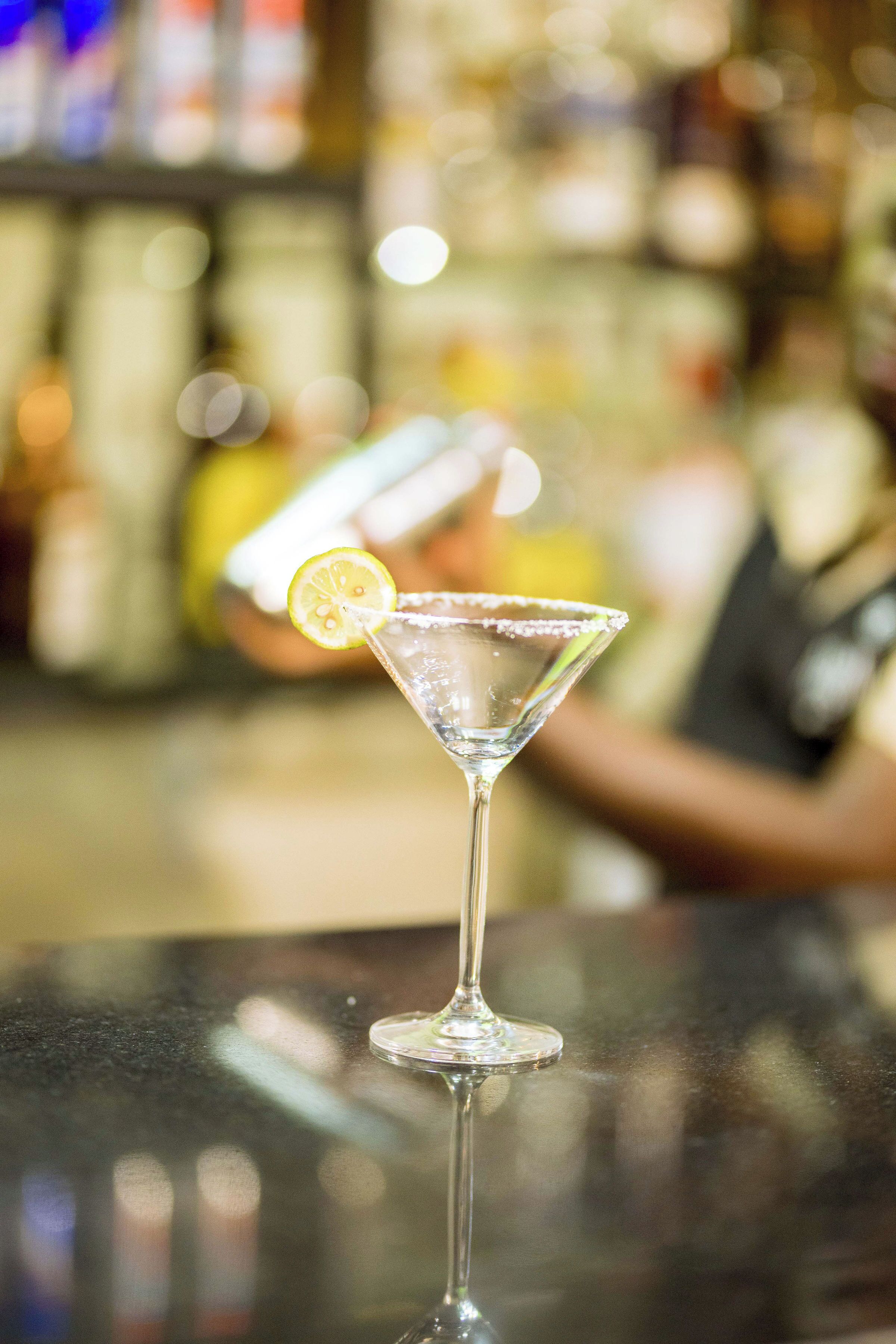 Ein Martini-Glas mit Zitronenscheibe auf einer Bar.