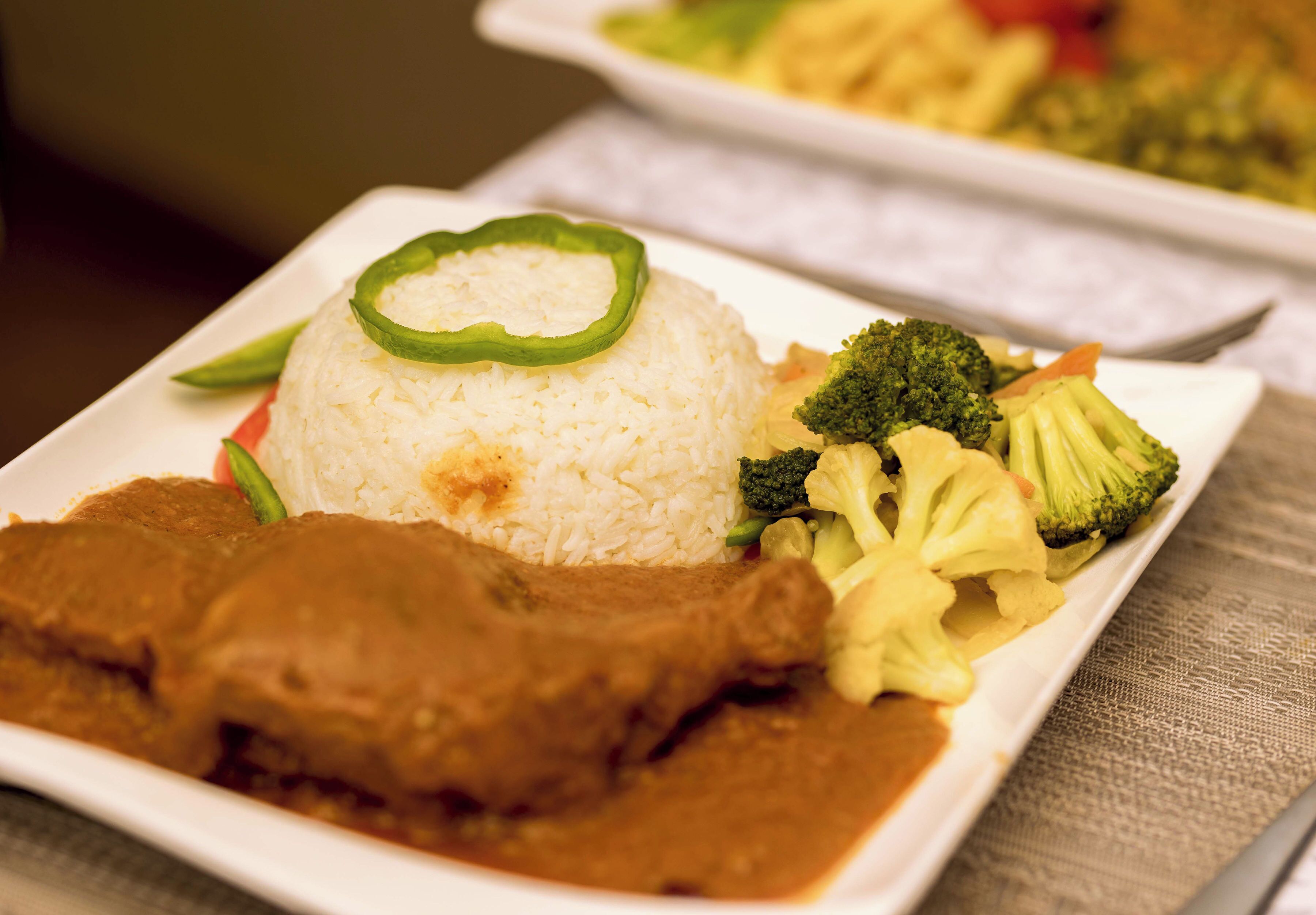 Un plato de comida con arroz, brócoli y un guiso de carne.