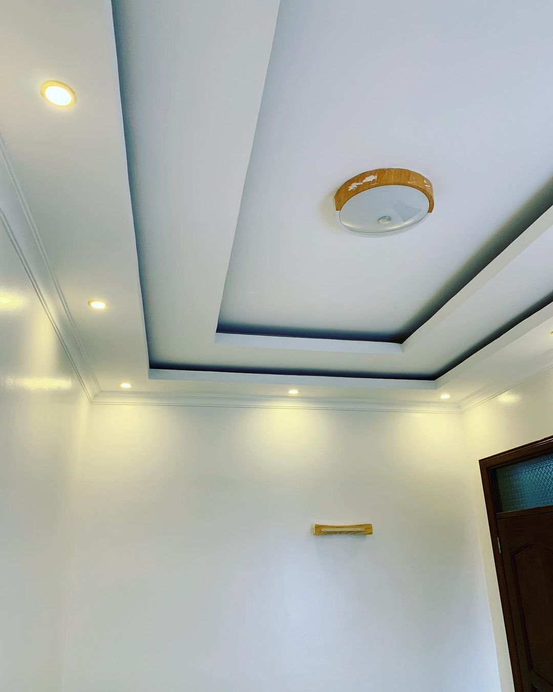 A ceiling with recessed lighting and a central circular light fixture.