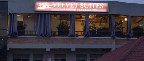 A hotel named 'Velvet Suites' with a sign indicating it is 'The One Made for a King'.
