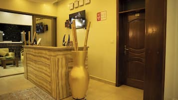A reception area with a wooden reception desk, a large vase, a clock, and a door labeled 201.