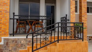 A staircase with ornate black railings leading to a wooden platform. - Velvet Suites (Kigali)