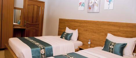 Habitación de hotel con dos camas, cabeceros de madera, un armario de madera y obras de arte en la pared.