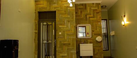 A hotel lobby with a herringbone-patterned wall, a white sink, and a water dispenser.
