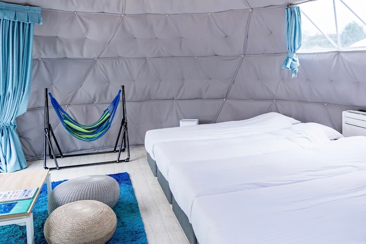 A tent-style room with two beds, a hammock, and a small table with a book.