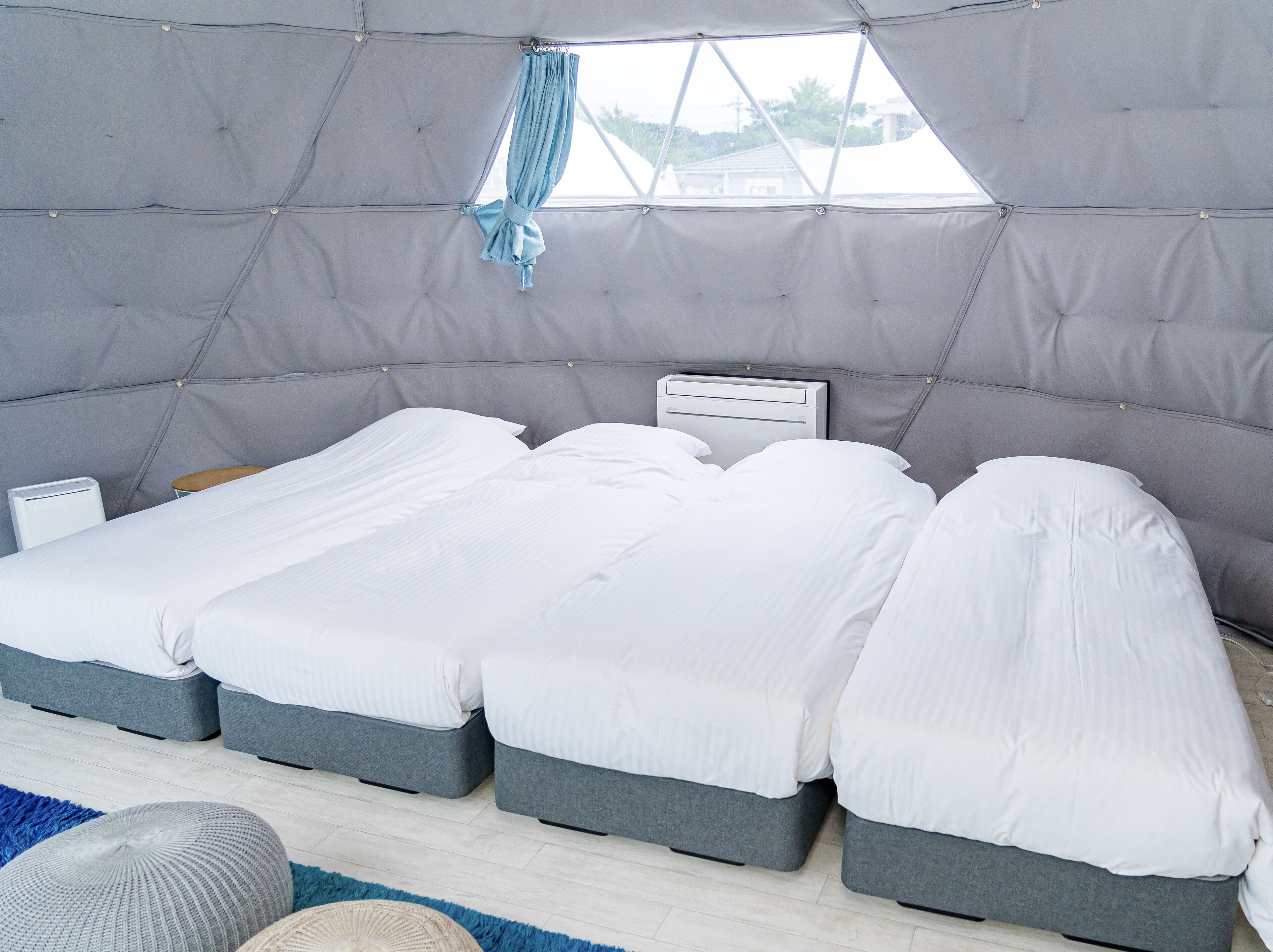 Un dormitorio moderno y compacto con una cama litera, una mesita de noche pequeña y una ventana con vistas al exterior.