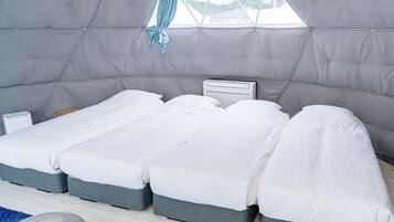 Un dormitorio moderno y compacto con una cama litera, una mesita de noche pequeña y una ventana con vistas al exterior.