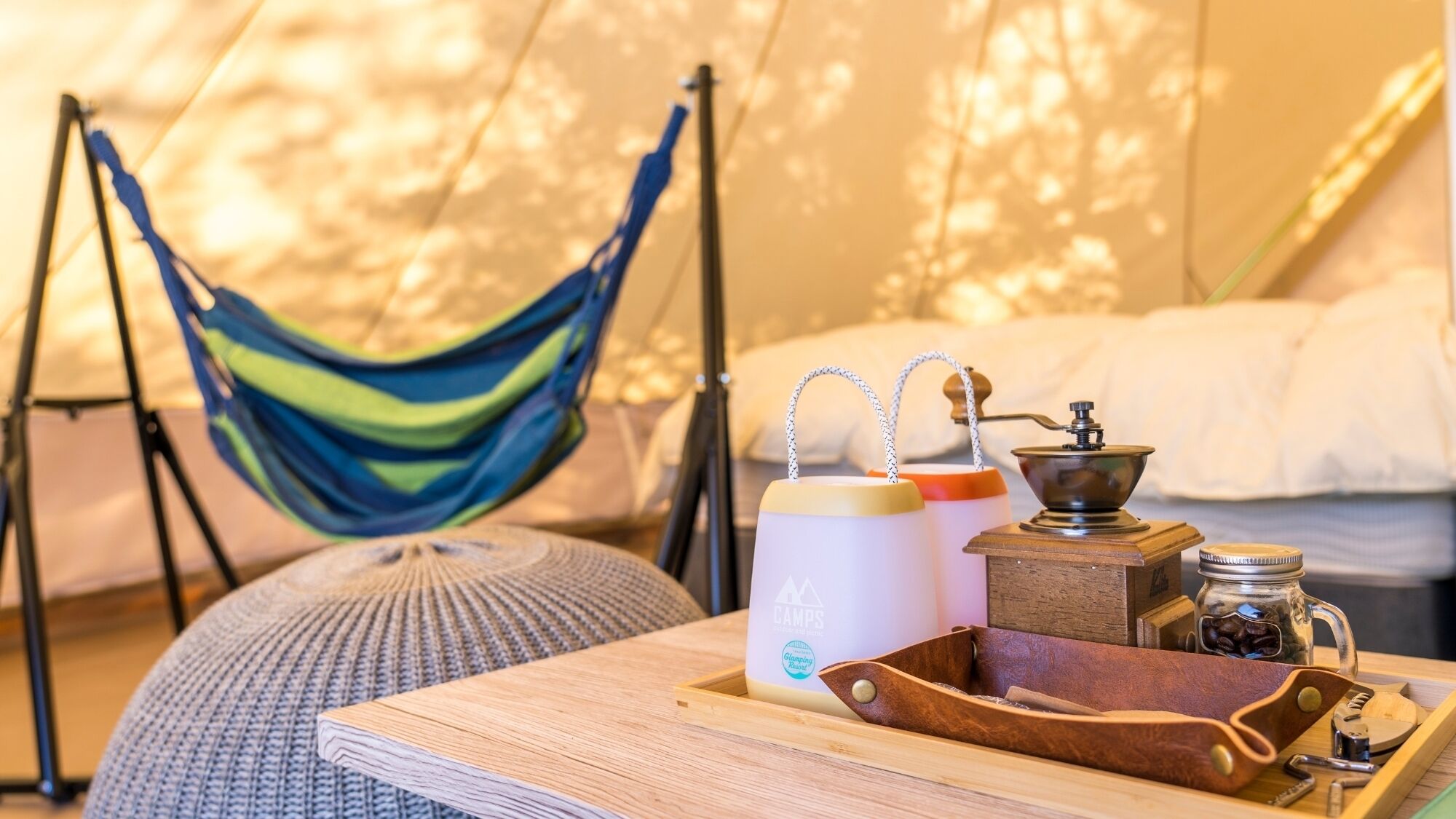 A hammock, a bed with white bedding, a coffee maker, and a tray with a leather case and utensils.