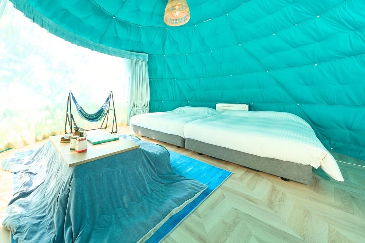 A tent-style room with a bed, a table with items, and a hammock.
